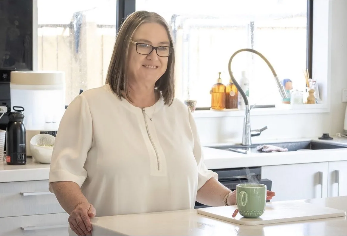 Michelle standing at her kitchen bench, smiling toward the camera