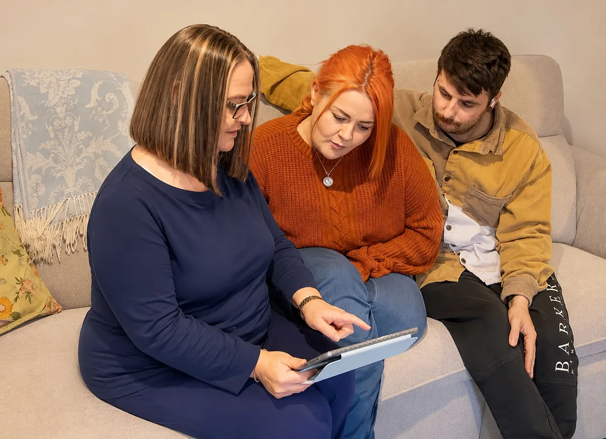 Michelle sitting with both new parents on their couch, going through a plan on a tablet